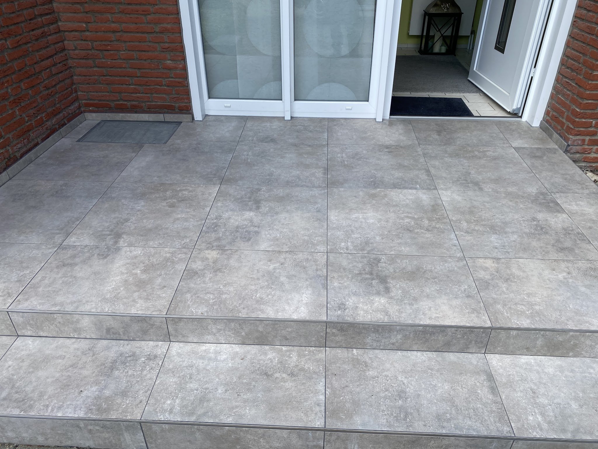 Terrasse vor dem Haus mit großformatigen Fliesen und Stufe