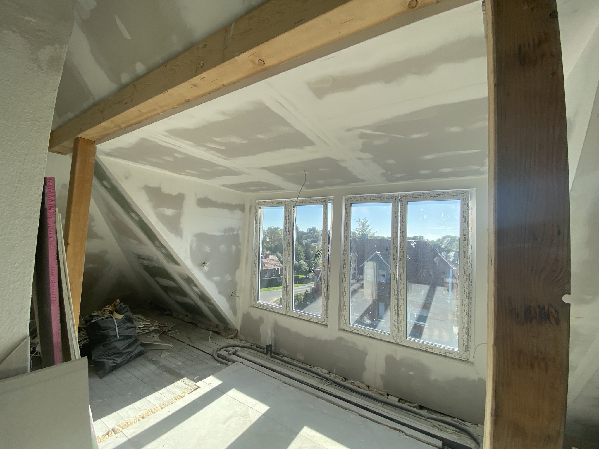 Dachgeschoss im Ausbau mit verspachtelten Gipskartonplatten und Fensterfront